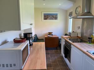 a kitchen with a microwave and a stove top oven at Burnside & Jocks Cottage on the Blarich Estate in Rogart