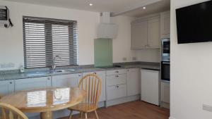 a kitchen with white cabinets and a wooden table at Courtbrook Farm Apartments in Exeter +6 photos