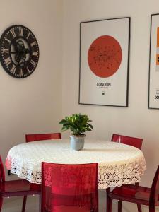 ペスカーラにあるLa casetta di Sasà intero appartamentoのダイニングルームテーブル(赤い椅子、時計付)