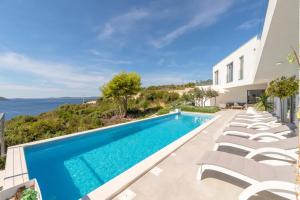a swimming pool with lounge chairs next to a house at Villa Marvela - Family 4 Bedroom in Maslinica