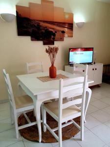 マンタ・ロータにあるDon Rodrigues Apartment - Manta Rotaの白いダイニングテーブル(白い椅子付)、テレビが備わります。