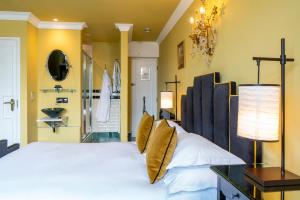 a bedroom with a large white bed with yellow walls at Burgh Island Hotel in Bigbury on Sea