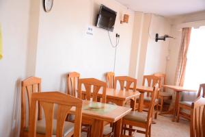een eetkamer met houten tafels en stoelen bij New Green Pastures Guest House in Eldoret