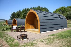 a large black and brown building with a table and a grill at Braeview Glamping in Eyemouth