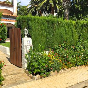 a garden with flowers and a statue in front of a hedge at DAMA Villa con piscina privada in Miami Platja