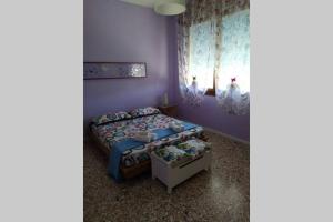 2 Betten in einem Zimmer mit lila Wänden in der Unterkunft ChiaraDiLuna - Appartamento con giardino privato in Cavallino-Treporti