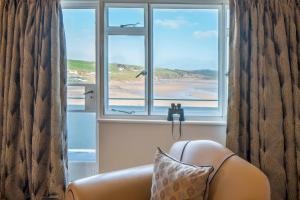 a chair in front of a window with a view of a beach at Burgh Island Hotel in Bigbury on Sea