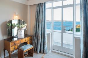 a room with a mirror on a dresser and a window at Burgh Island Hotel in Bigbury on Sea