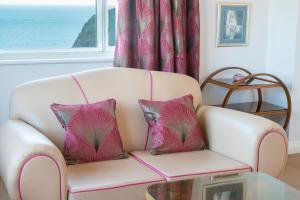 a white couch with two pink pillows on it at Burgh Island Hotel in Bigbury on Sea