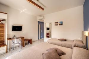 a bedroom with two beds and a desk and a tv at Hotel Florida in Sorrento