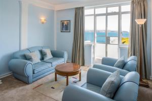 a living room with blue couches and a table at Burgh Island Hotel in Bigbury on Sea