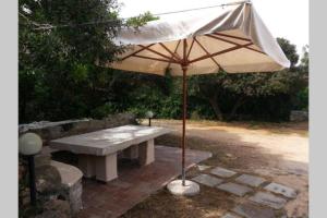 a picnic table with an umbrella on a brick patio at Giardinelli Vacanze La Maddalena, SARDEGNA, Italia in La Maddalena