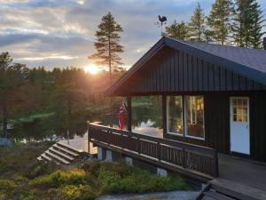 a house with the sun setting in the background at Solhytta Fantastisk beliggenhet! Hytte til leie på Skrim! in Kongsberg +53 photos