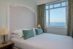 a bedroom with a large bed with a large window at Burgh Island Hotel in Bigbury on Sea