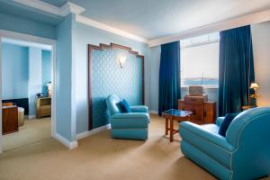 a blue living room with blue chairs and a table at Burgh Island Hotel in Bigbury on Sea