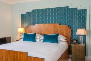 a bedroom with a large bed with blue pillows at Burgh Island Hotel in Bigbury on Sea