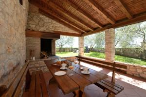 um pátio exterior com uma mesa de madeira e uma lareira em House Mariano em Baldaši
