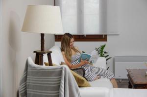 a woman sitting on a couch reading a book at Syros Luxury Seaview Wellness Suite Finikas in Finikas