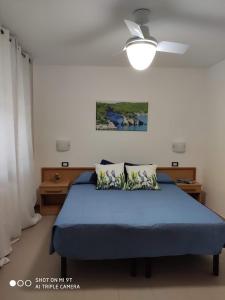 een slaapkamer met een blauw bed en een plafondventilator bij Residence Carabella in Vieste