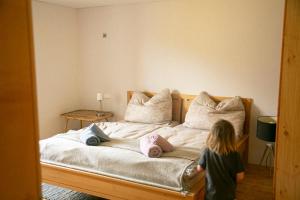 a little girl standing on a bed with pillows at Rosa - Huusa im Bregenzerwald in Au im Bregenzerwald