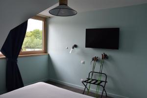 a bedroom with a bed and a television on the wall at Hôtel Domaine du Lac Chambon in Murol