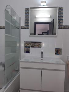 W białej łazience znajduje się umywalka i lustro. w obiekcie Pedras d'el Rei - Casa Mira w mieście Tavira