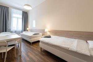 a bedroom with two beds and a table and a desk at East Station DeLuxe in Budapest