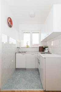 eine weiße Küche mit weißen Schränken und einem Waschbecken in der Unterkunft Apartments Jasna 3 in Novigrad Istria