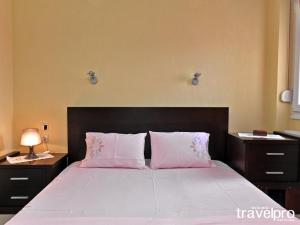 a bedroom with a large bed with two pink pillows at Villa Vangelis in Nea Plagia