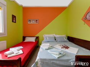 two beds in a room with green and orange walls at Villa Vangelis in Nea Plagia