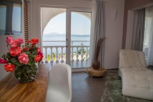 a living room with a vase of flowers and a balcony at Pantokrator Hotel in Barbati