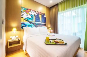 a hotel room with a bed with a tray of food on it at MaxOneHotels at Resort Makassar in Makassar