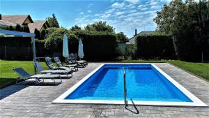 una piscina con sillas y sombrillas en un patio en Nefelejcs Apartmanház, en Gyenesdiás