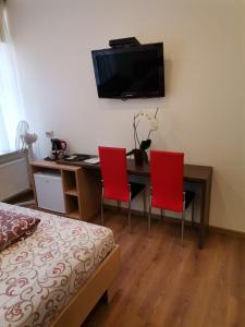 a bedroom with a desk with two red chairs and a television at Guest house Baltika in Ventspils