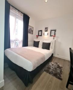 a large white bed in a room with a window at Hôtel Le 23 in Clichy