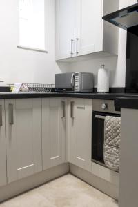 a kitchen with white cabinets and a black counter top at 2A SPV Double En-suite Room in Wakefield