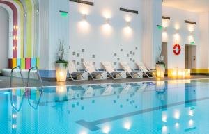 une piscine avec des chaises blanches et une piscine dans l'établissement Orhideea Residence & Spa, à Bucarest