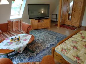 a living room with a tv and a couch and a table at 4 Sterne-Haus am See in Waren