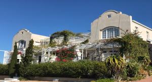 a large white building with flowers and plants at Charlotte House in Stilbaai