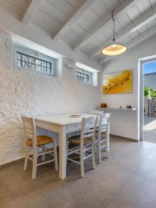 a white dining room with a white table and chairs at ONOS RESIDENCE in Hydra