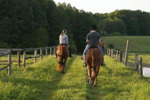 dos personas montando a caballo en un campo en Gut Sarnow - Hotel, Restaurant und Reitanlage, en Schorfheide