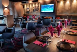 un restaurante con mesas, sillas y TV en Schönblick Residence - Absolut Alpine Apartments en Zell am See