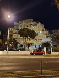 un coche rojo estacionado frente a un edificio por la noche en Playa entre pinares en El Portil