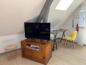 una TV su supporto in legno in una stanza con tavolo di SUPERLOGIS - Sous Les Toits - T2- 3étoiles - BLOIS-HYPERCENTRE 1 chambre 4 personnes a Blois
