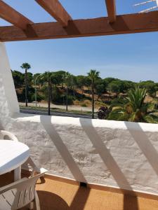 a balcony with a table and chairs and palm trees at Playa entre pinares in El Portil