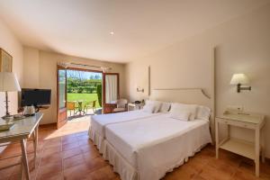 Schlafzimmer mit einem Bett, einem Schreibtisch und einem TV in der Unterkunft Son Corb Boutique Hotel in Cala Bona