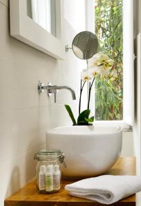 La salle de bains est pourvue d'un lavabo et d'une fenêtre fleurie. dans l'établissement San Pietro Boutique Rooms, à Rome