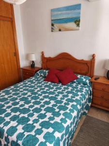 a bedroom with a blue and white bed with two red pillows at Playa entre pinares in El Portil