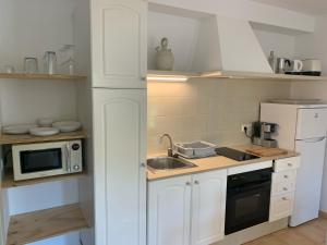 a white kitchen with a sink and a microwave at Es Cucó in Cala Galdana