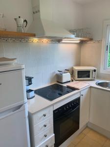 a small kitchen with a stove and a microwave at Es Cucó in Cala Galdana